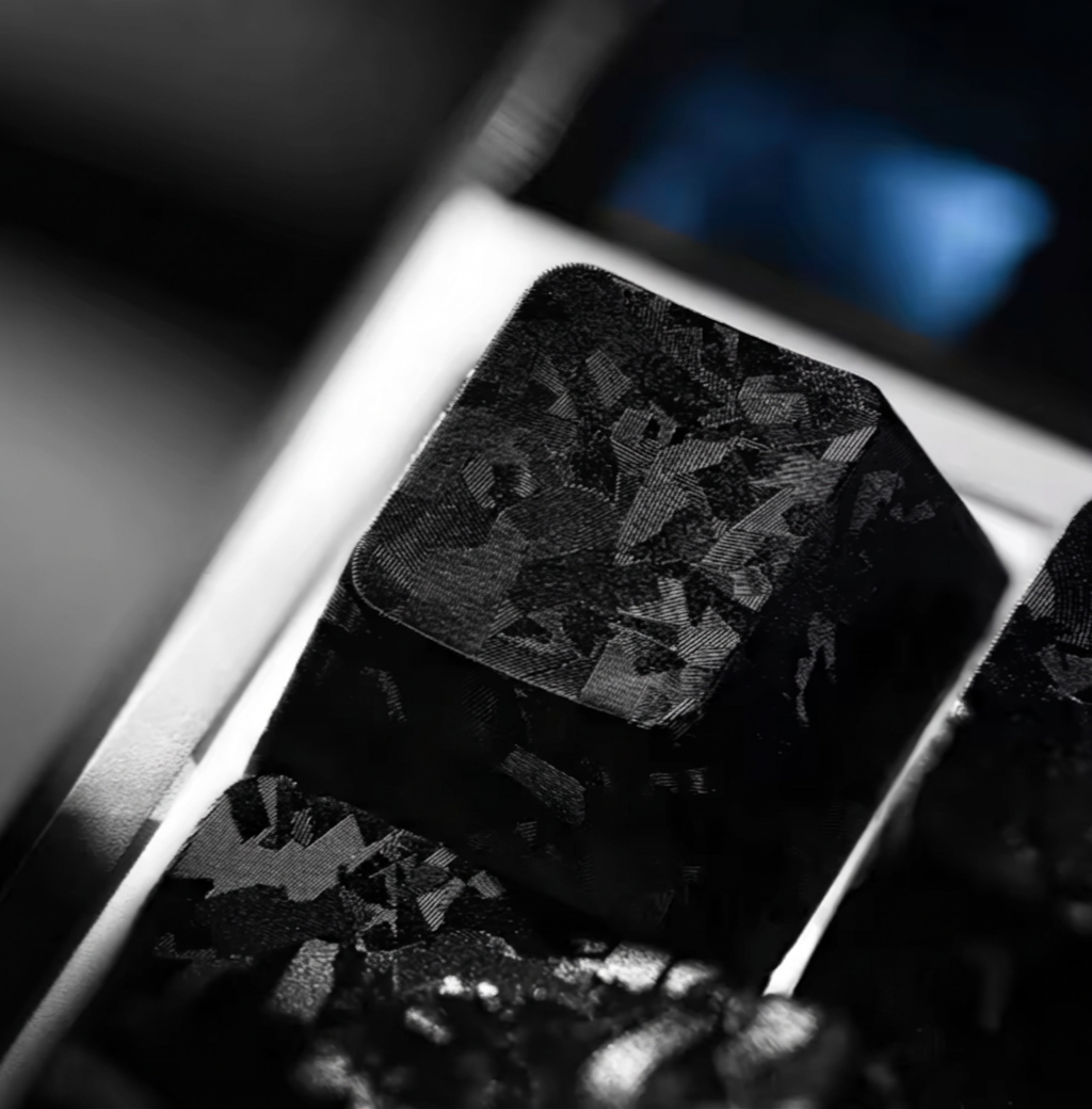 Close-up of a black stone with intricate patterns on a reflective surface. A carbon forged keycap